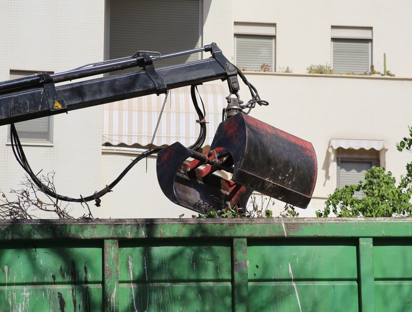 Grapple crane loading construction debris into a dumpster