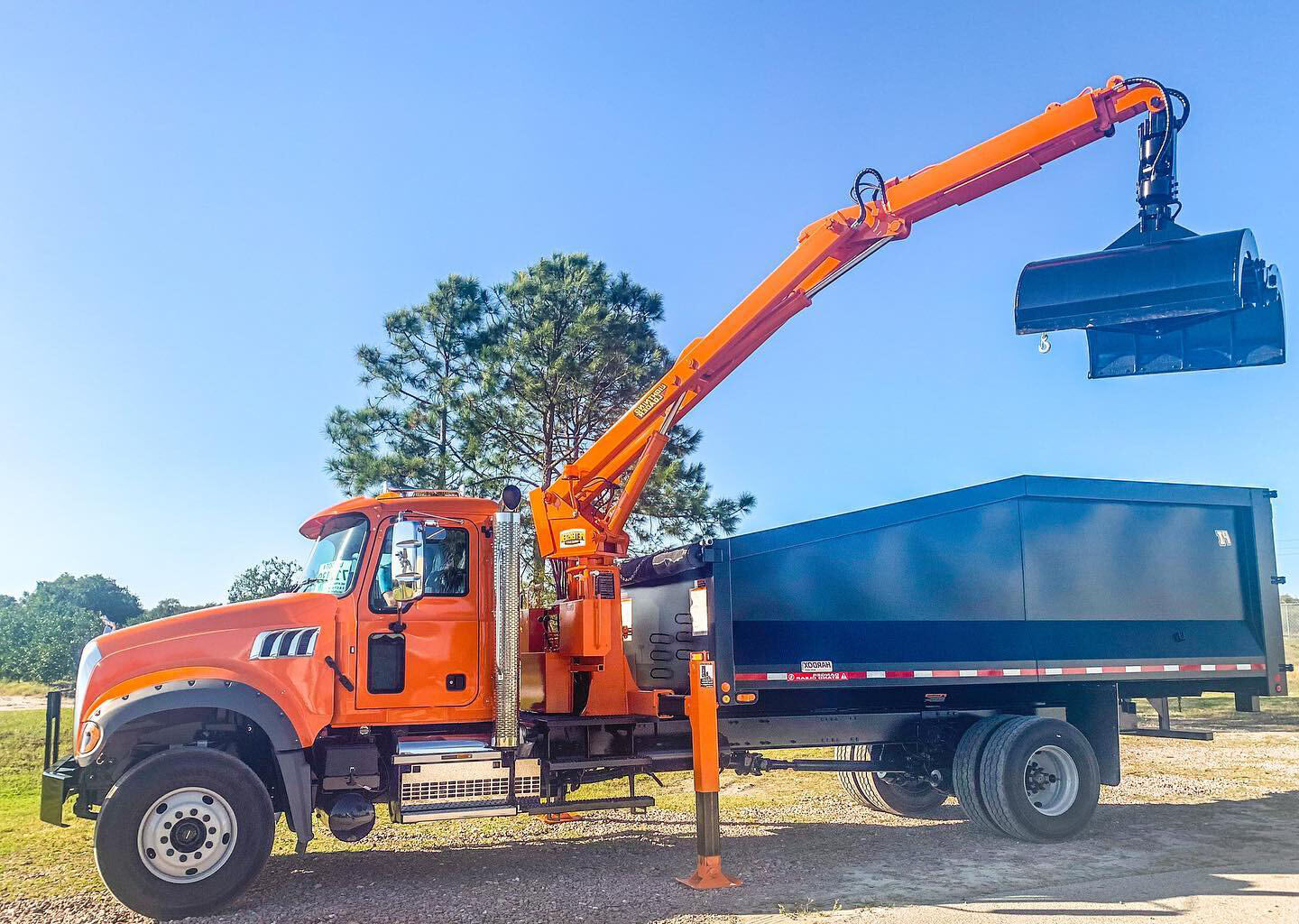 Grapple truck claw grabbing a brush and yard waste pile